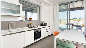 Et moderne køkken med spiseplads, store vinduer og udsigt til en pool.