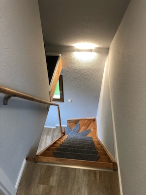 Staircase with carpeted landing and wooden handrail.