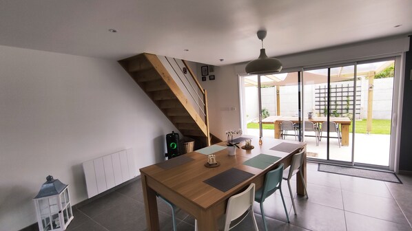 A modern kitchen with a wooden table, chairs, and a staircase leading to a balcony.