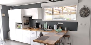A modern kitchen with white cabinets, a wooden countertop, and a window with a view of the outdoors.