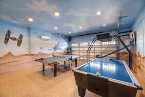 Sala de lazer com mesa de bilhar, pingue-pongue e cesta de basquete.