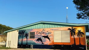 Un bâtiment orné d’une fresque représentant des dauphins et des palmiers, portant l’inscription « The Dolphin Inn ».