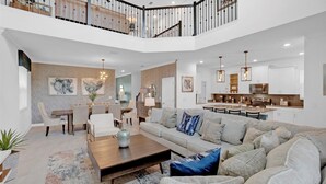 A spacious living area with a high ceiling, a dining area, and a kitchen. - 3 Miles Disney/Games Room/PS4/3 Themed Bedrooms/Private Pool/ON STOREY LAKE Wifi (Kissimmee)