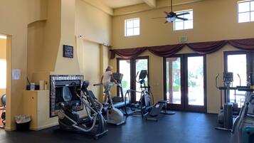 A gym with exercise equipment, a ceiling fan, and a motivational sign.