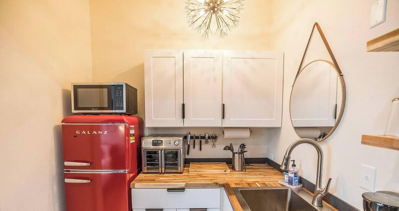 Une cuisine compacte avec un réfrigérateur Galanz rouge, un grille-pain et un four à micro-ondes posés sur le plan de travail.