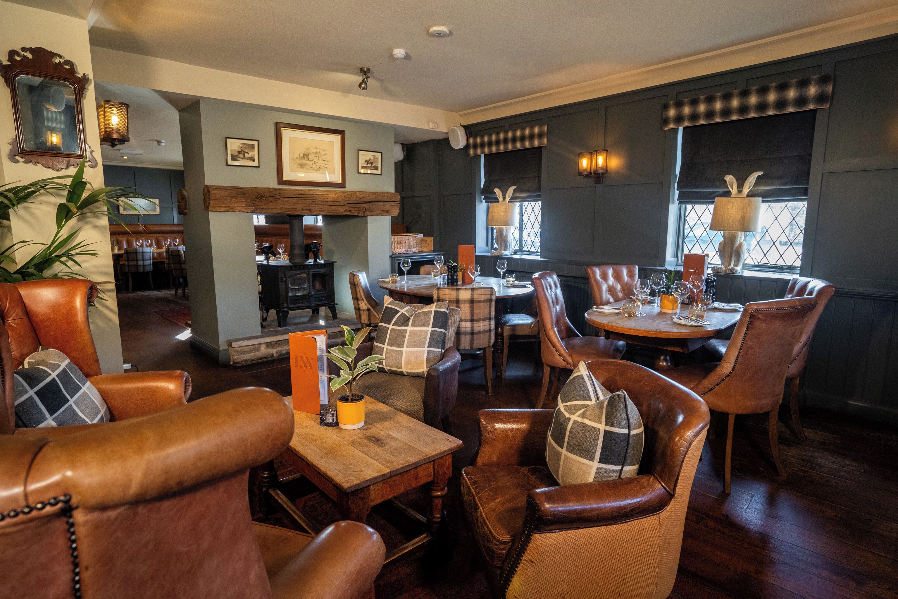 A dining area with leather chairs, a wooden table, and a fireplace.