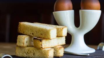 A stack of white bread slices and a white ceramic holder with two brown eggs on top.
