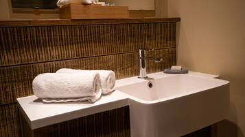 A modern bathroom with a wooden vanity, a white sink, and a towel placed on the counter.