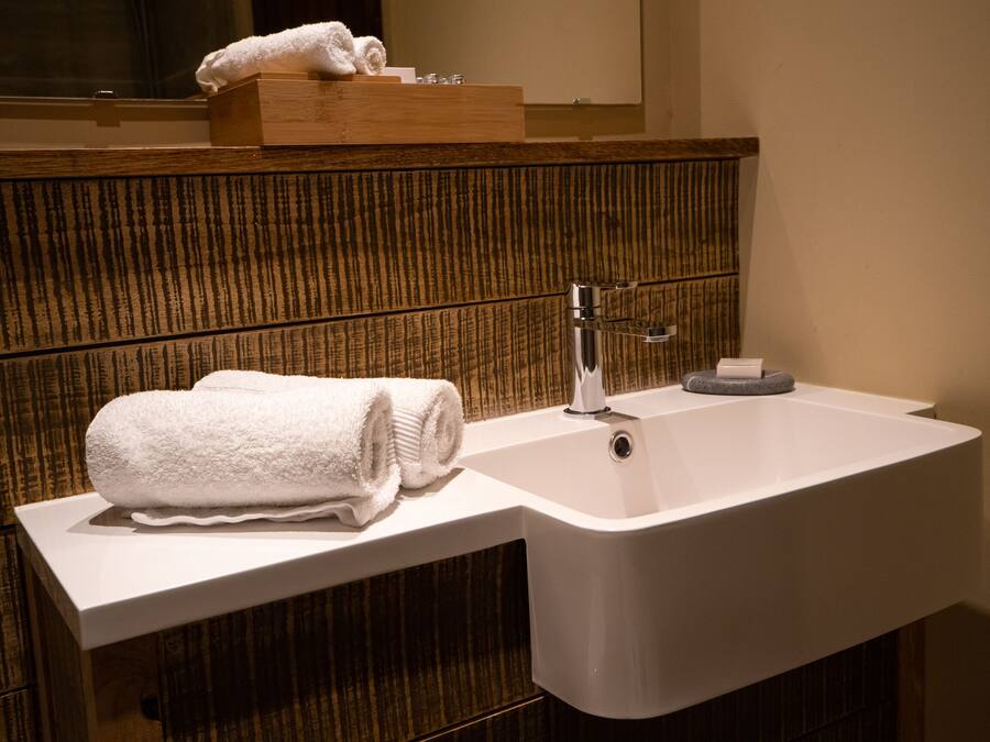 A modern bathroom with a wooden vanity, a white sink, and a towel placed on the counter.