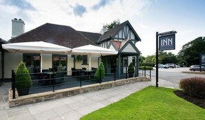 Un hotel con mesas al aire libre y un patio cubierto.