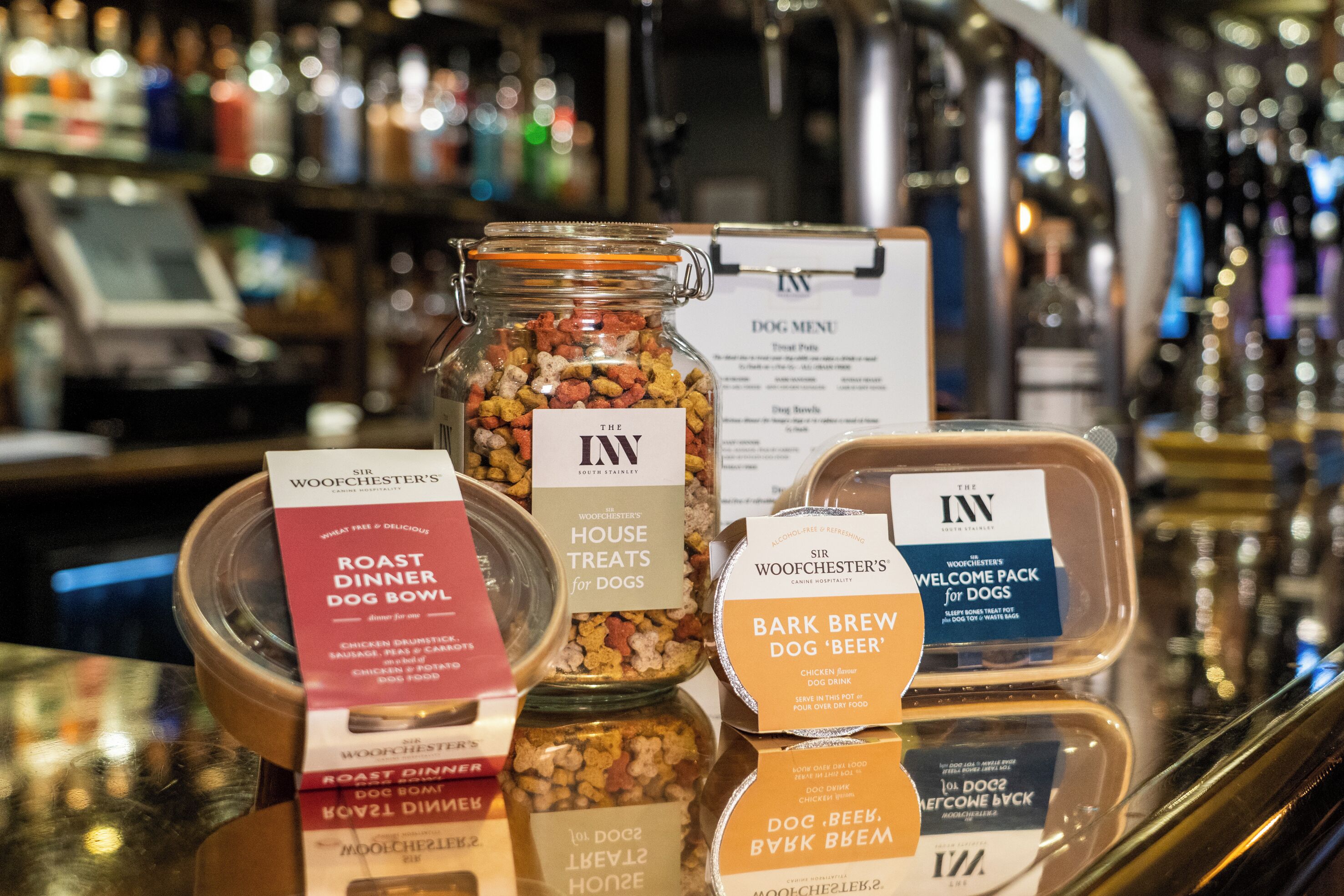 On pouvait voir une variété de produits pour chiens exposés sur un comptoir, notamment un bocal étiqueté « The Inn » et plusieurs autres contenants portant des étiquettes.