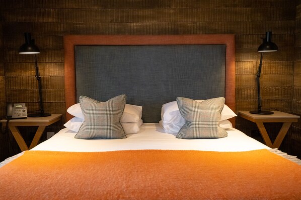 Una habitación de hotel con una cama grande, dos lámparas de noche y un teléfono en la mesita de noche.