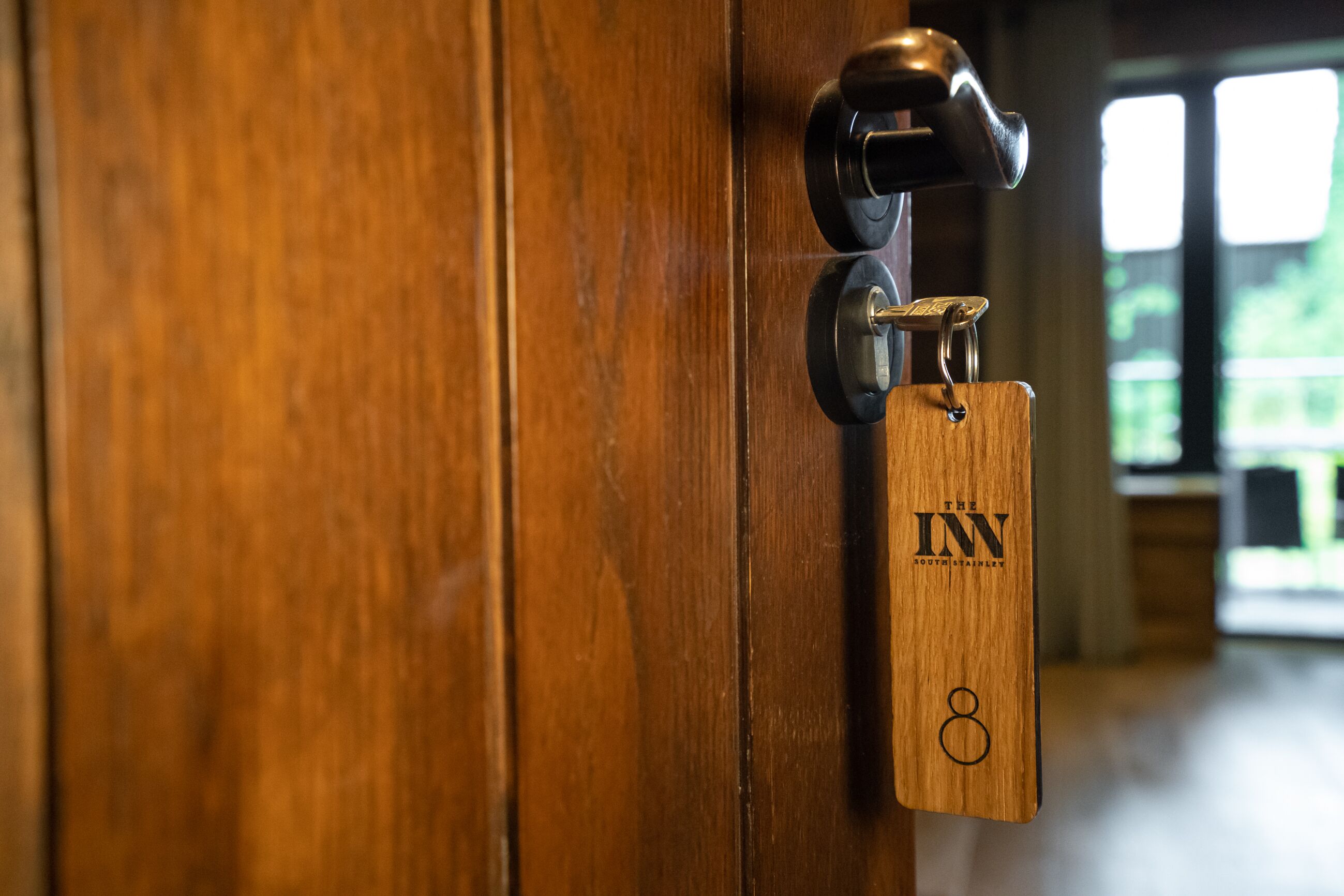 A wooden door with a keyhole and a keychain with "The Inn" and the number 8.
