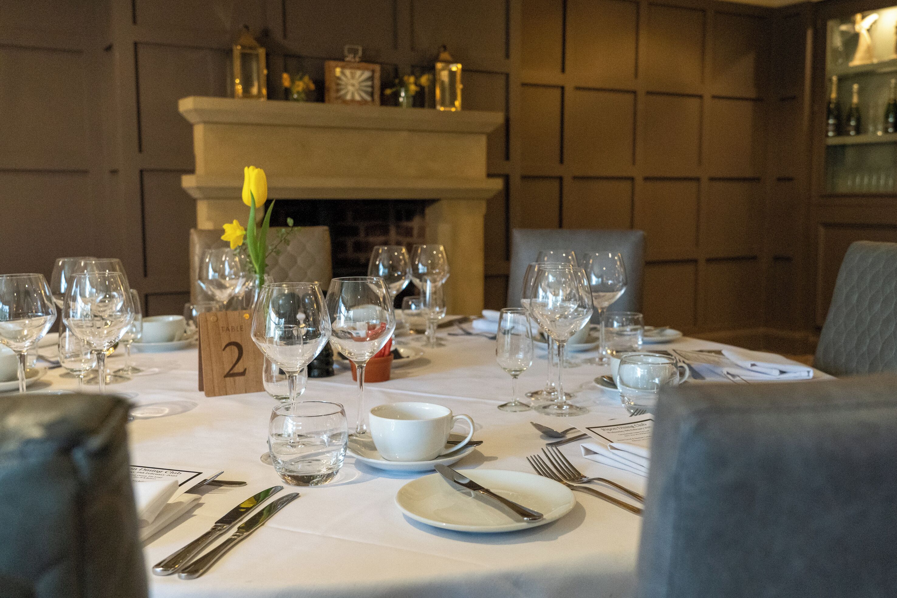 A dining table set for a meal with wine glasses, plates, and cutlery.