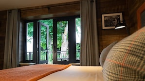 A hotel room with a bed, a window with curtains, a view of trees, and a framed picture on the wall. - The Inn South Stainley (Harrogate)