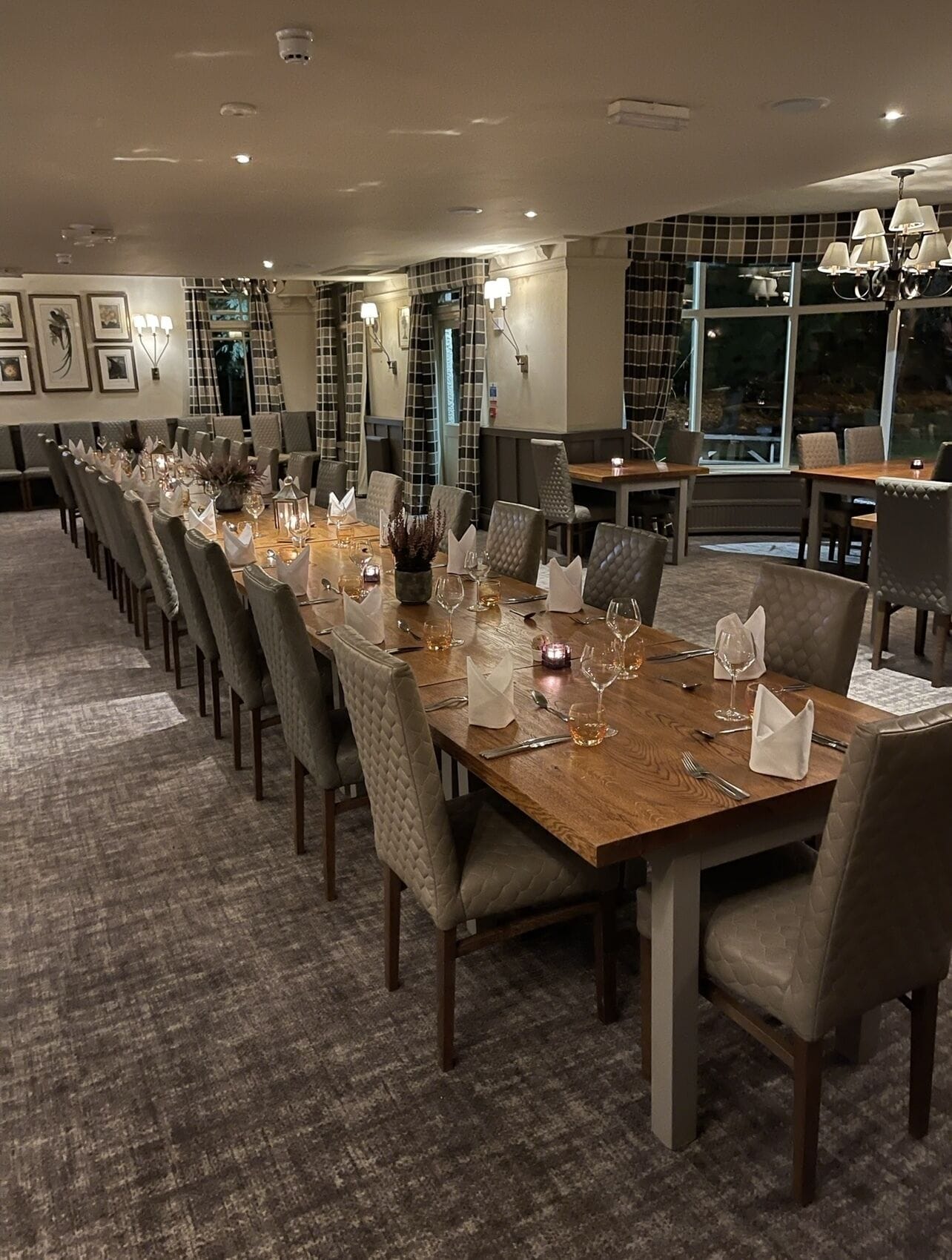 A long dining table set for a formal event, with chairs and table settings including wine glasses and candles.