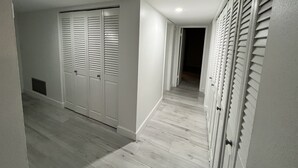 Ein Flur mit Holzboden, weißen Wänden und einem Schrank mit Klappläden.