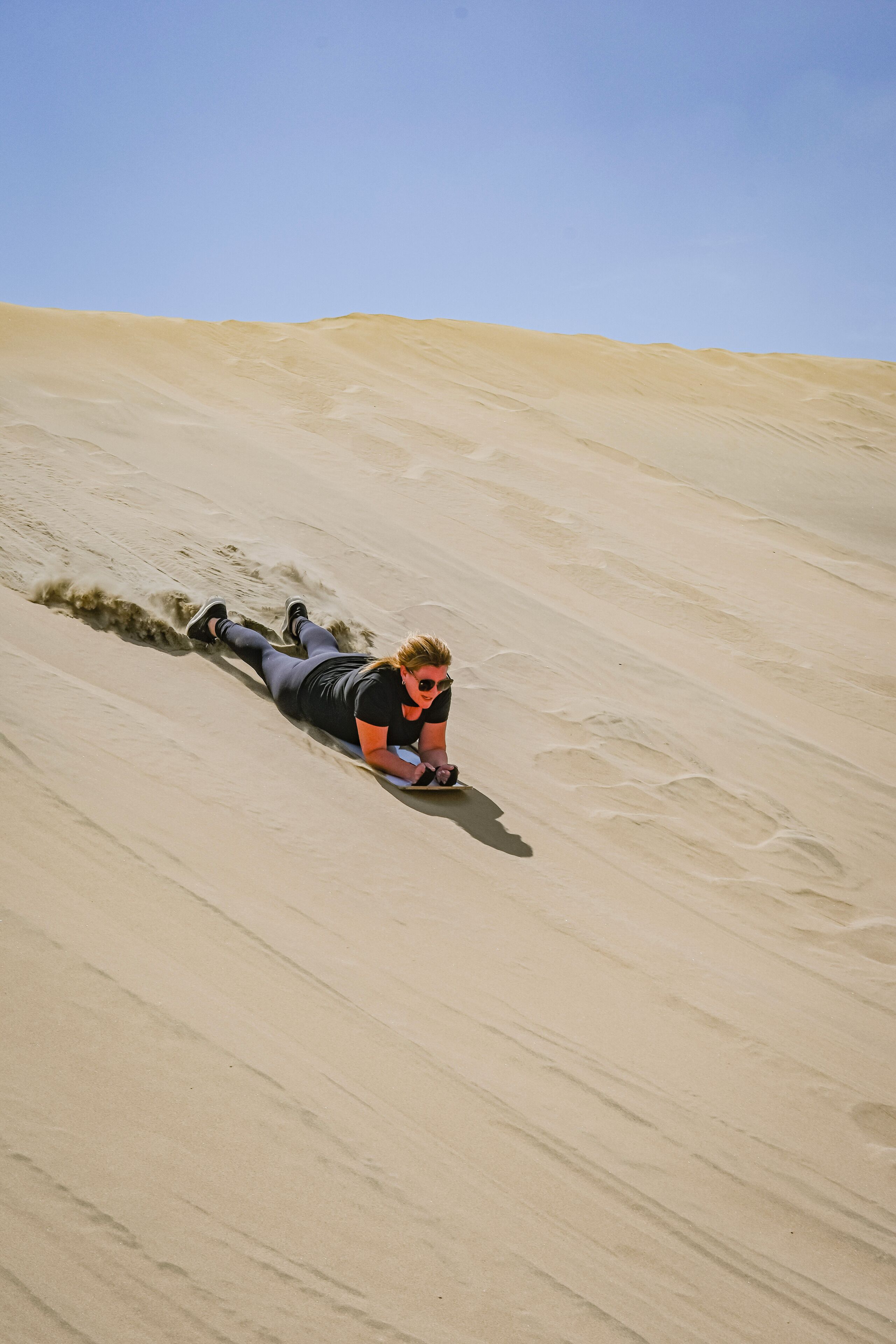 A person lying on a sandy slope.