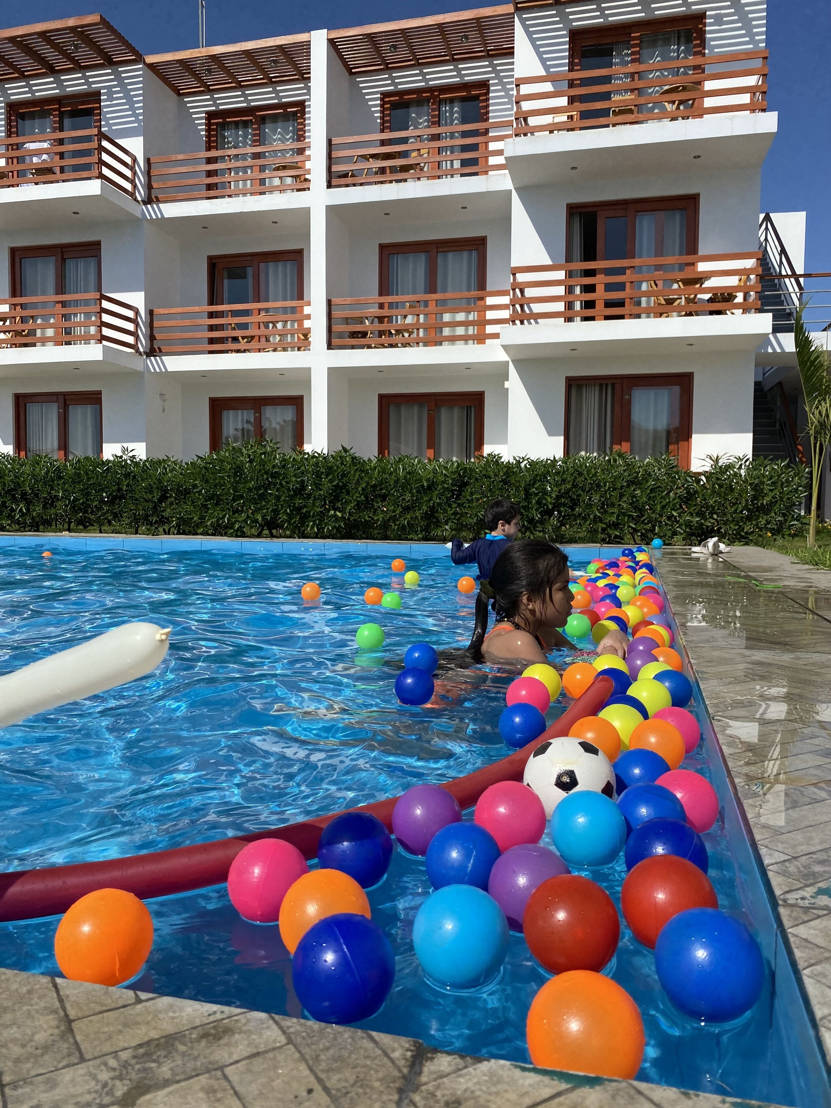 A swimming pool with colorful balls and a hotel building in the background.