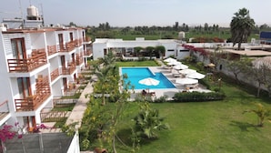 Un hotel con piscina, mobiliario exterior y jardín.