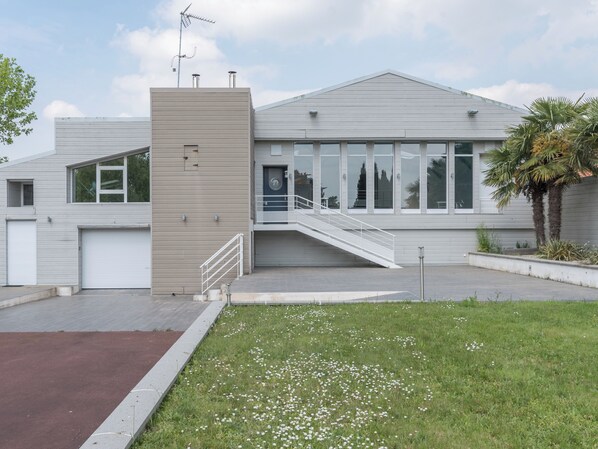 A modern building with a flat roof, large windows, and a central staircase leading to an entrance.