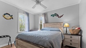 Une chambre à coucher avec un lit en bois, une table de chevet, une lampe et une fenêtre avec des rideaux.