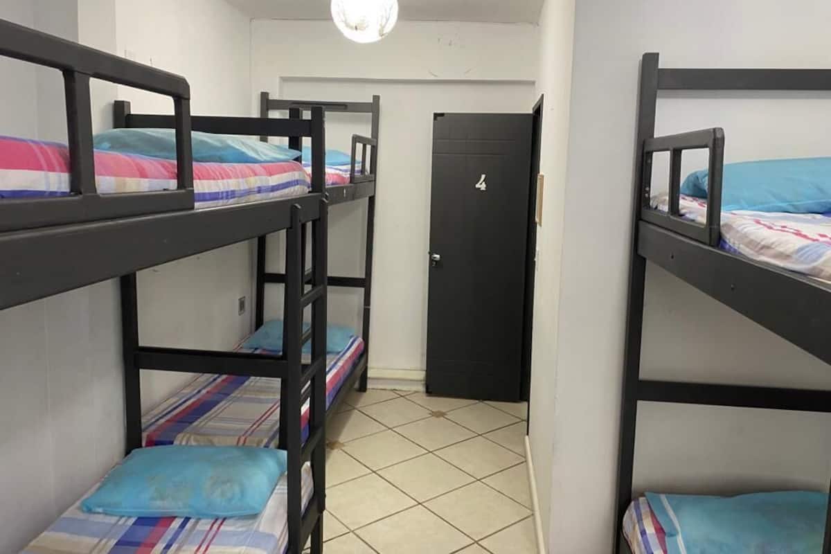 A dormitory room with bunk beds, a door, and a tiled floor.