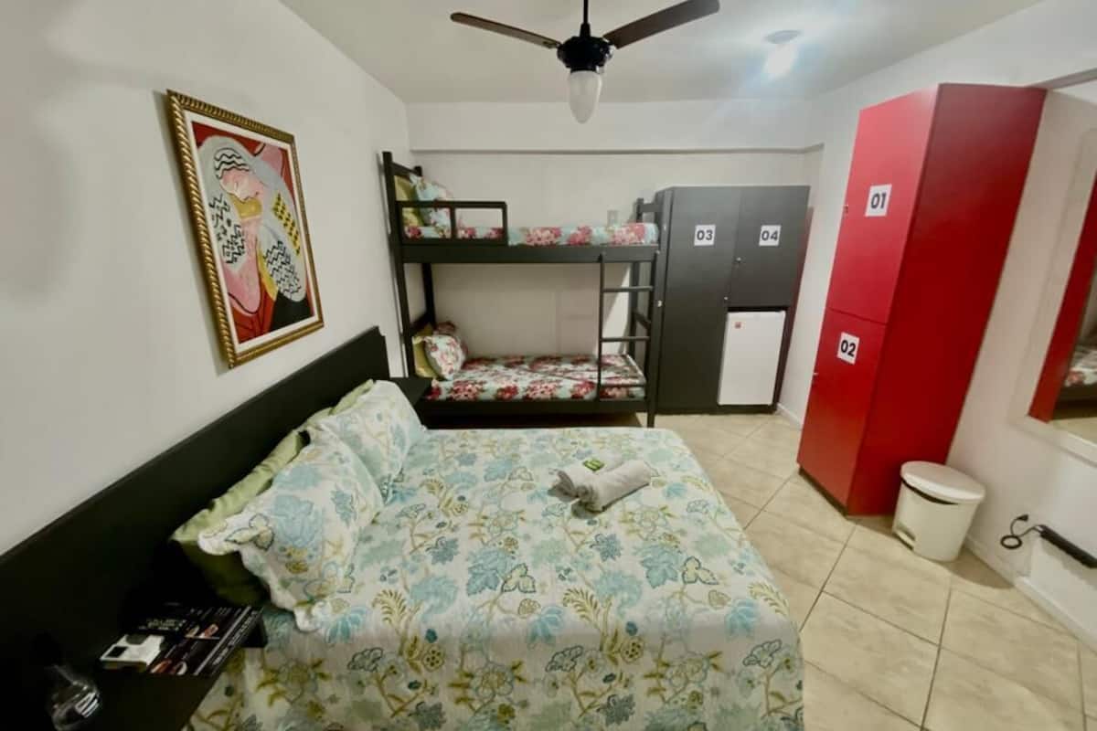 A room with bunk beds, a desk, a wardrobe, and a ceiling fan.