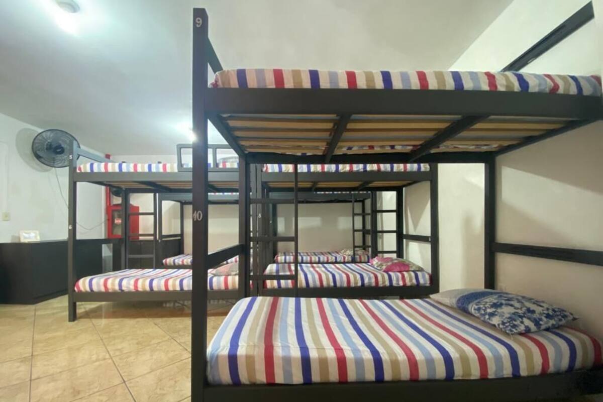 A bunk bed room with striped bedding and a fan.