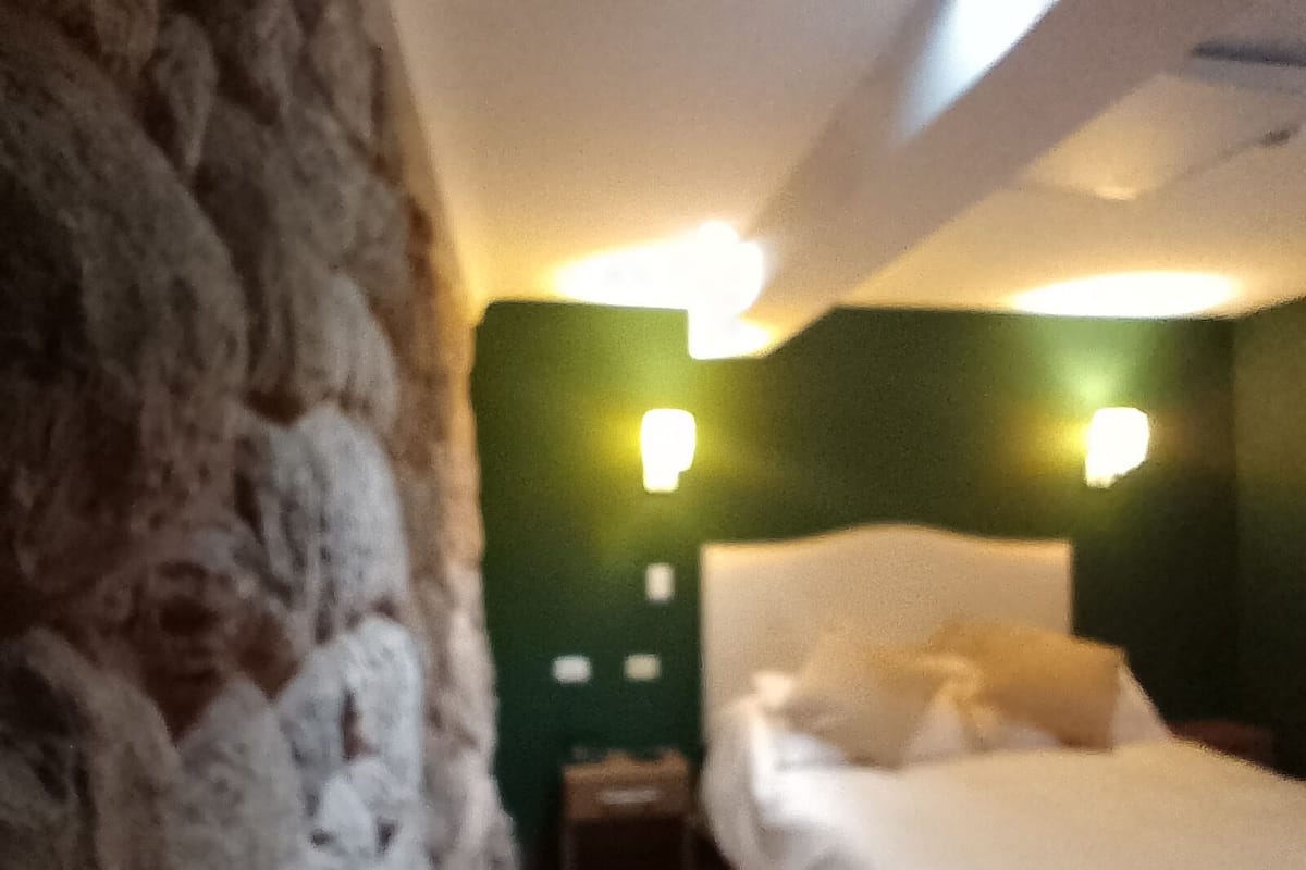 A room with a bed, a nightstand, and two wall-mounted lights.