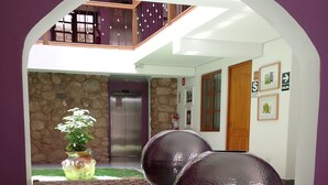 A modern lobby with a glass table, decorative vases, and a stone wall.