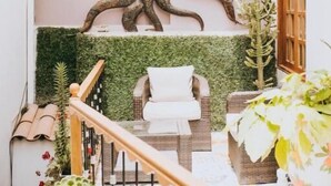 A staircase with a wall-mounted tree sculpture, a white chair, and a wooden door.