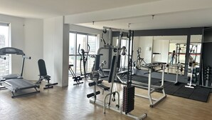 A spacious gym with various exercise equipment, large windows, and a mirror reflecting the space. - Apartamento 206 Saint Sebastian Flat Duo (Jaragua do Sul)