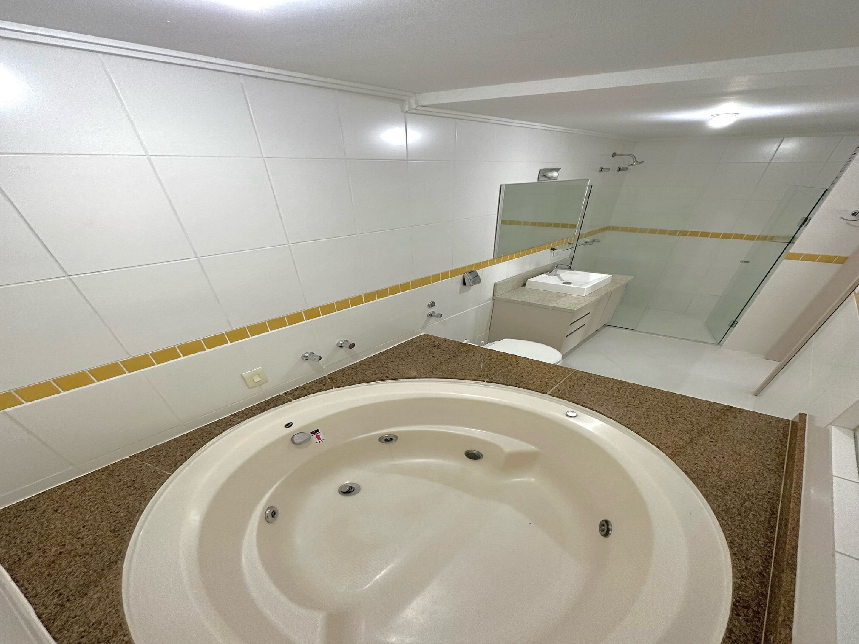 A modern bathroom with a large bathtub, a glass shower enclosure, and a small sink.