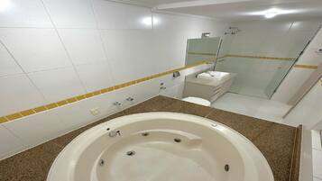 A modern bathroom with a large bathtub, a glass shower enclosure, and a small sink.