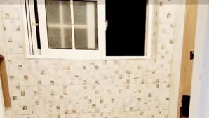 Ein Badezimmer mit gefliesten Duschwänden, einem kleinen Fenster und einem Marmorboden.