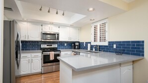 A modern kitchen with white cabinets, a stainless steel refrigerator, a microwave, and an oven. - CASA DE LA VIDA - Anasazi Village - Golf View (Phoenix)