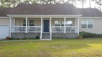 Stroll up to this charming home, featuring a welcoming front porch with a dark door and white railings.