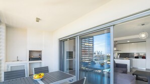 Un appartement moderne doté d’un balcon, d’un coin repas avec une table et des chaises, et d’une cuisine.