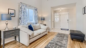A modern living room with a beige sofa, a dark side table, a blue lamp, and a patterned rug. - NEW Spacious Home Near Old Town Parker/Tech Ctr (Parker)