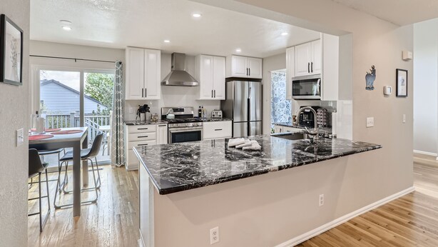 A modern kitchen with white cabinets, a large island, stainless steel appliances, and a view to the outside. - NEW Spacious Home Near Old Town Parker/Tech Ctr (Parker)