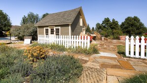 A small house with a white picket fence, a stone pathway, and a garden with various plants. - NEW Spacious Home Near Old Town Parker/Tech Ctr (Parker)