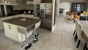 Una cucina moderna con isola centrale, elettrodomestici in acciaio inossidabile e zona pranzo con un tavolo grande e sedie.