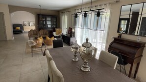 Un'ampia sala da pranzo con un lungo tavolo, diverse sedie e due vasi d'argento decorati.