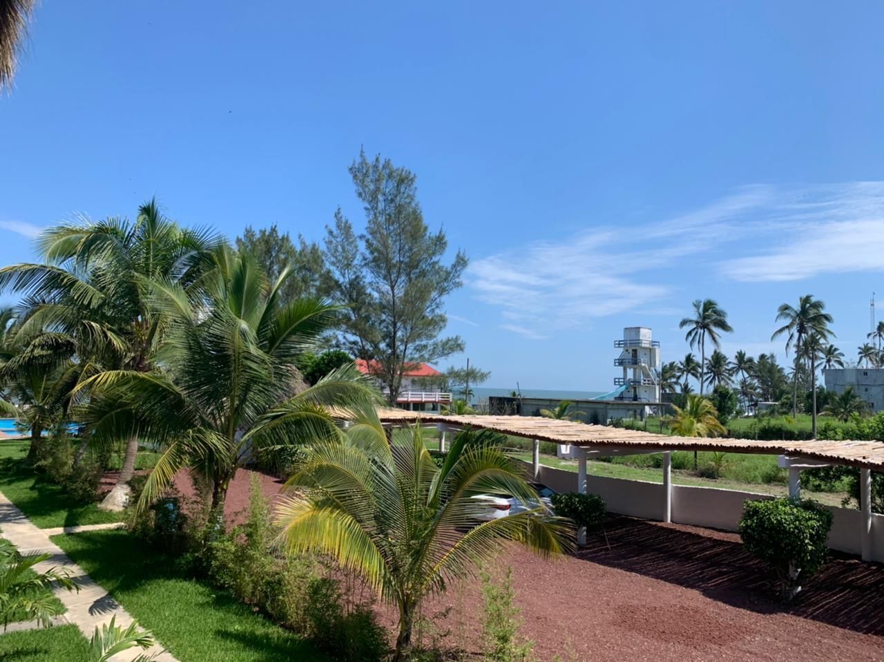 Un resort con un espacio al aire libre cubierto, palmeras y vista al océano.