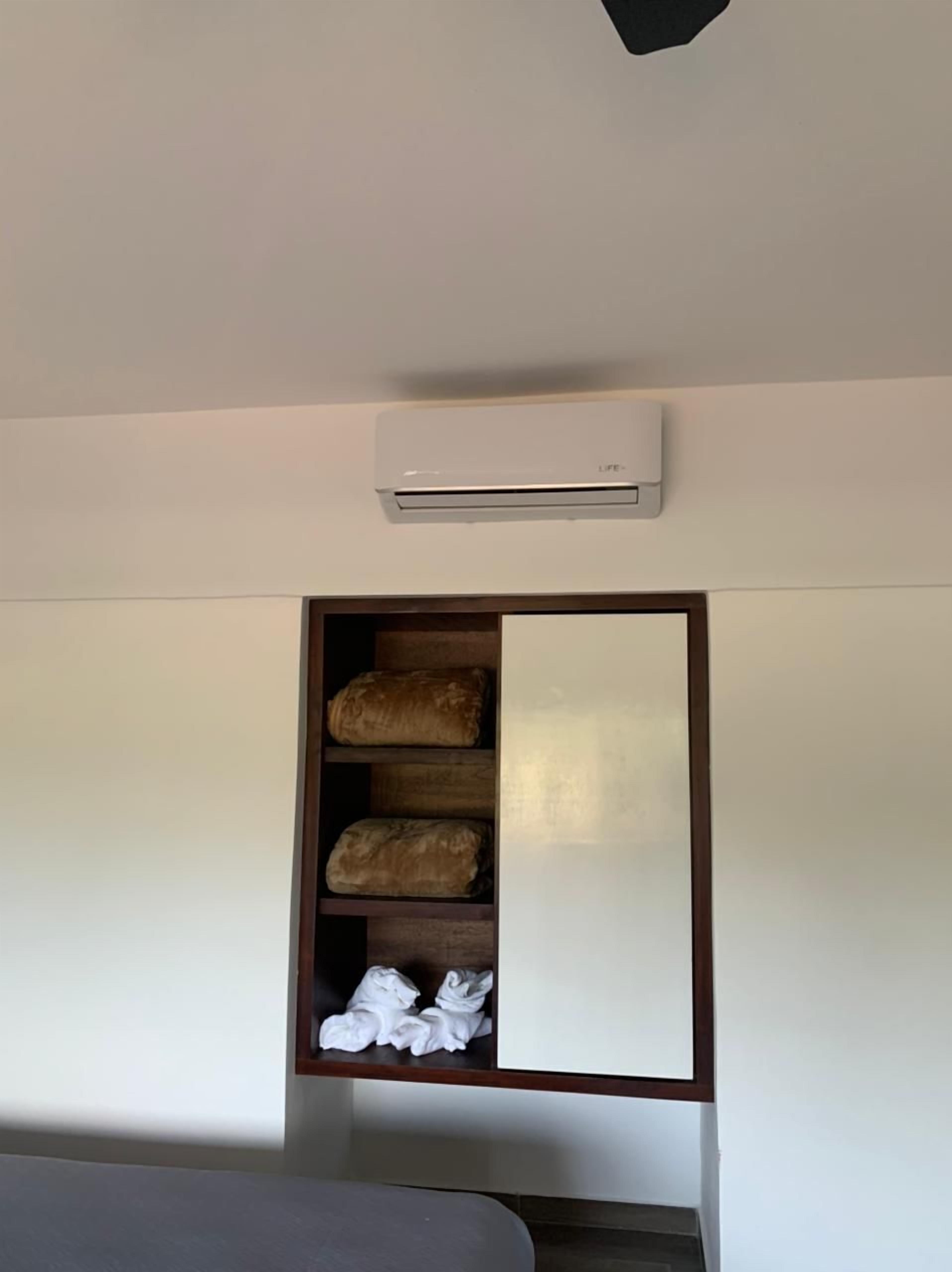 Een slaapkamer met een inbouwkast, een plafondairconditioner en een bed.