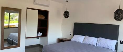Een slaapkamer met een bed, plafondventilator, spiegel, kledingkast en raam.