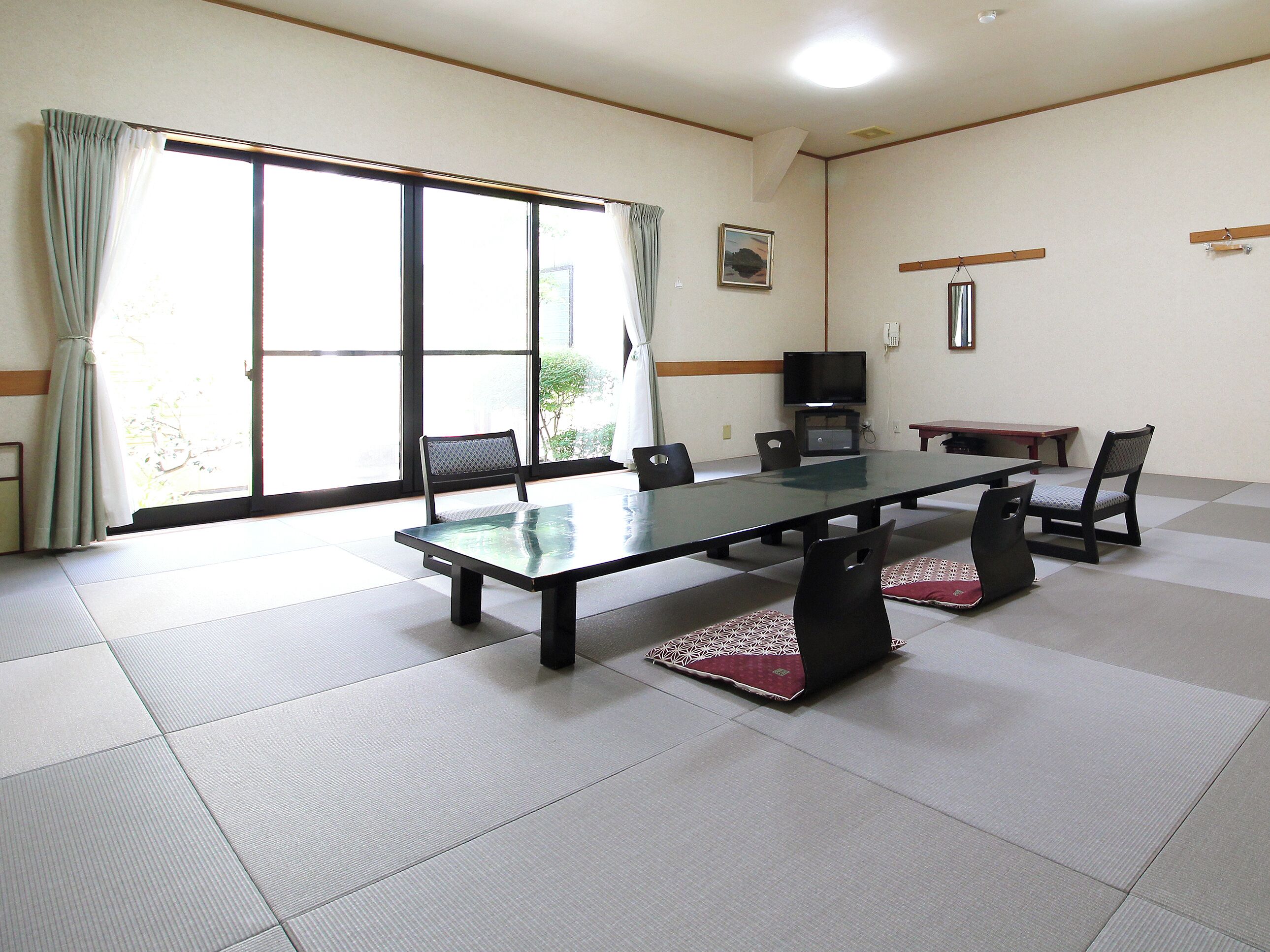 A conference room with a glass table, chairs, a television, and sliding glass doors.