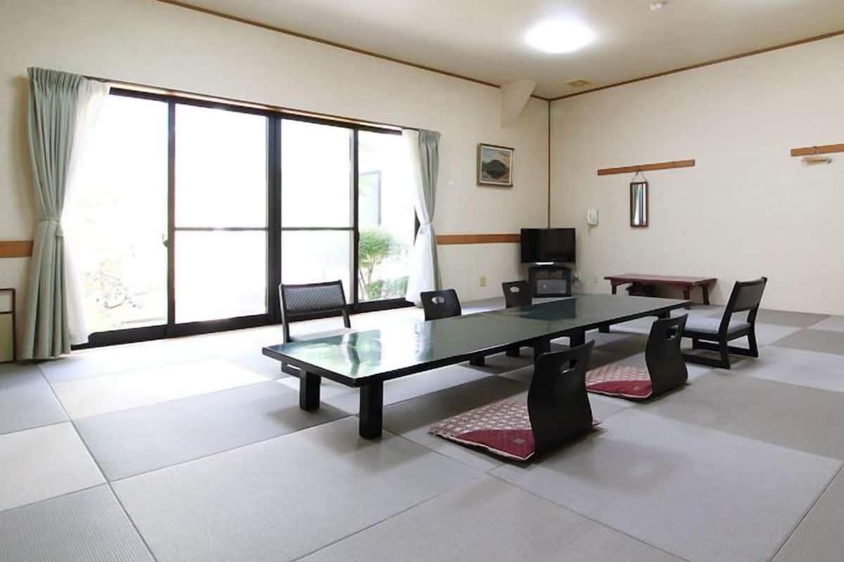 A conference room with a glass table, chairs, a television, and a sliding glass door.