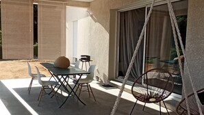 Un área de patio exterior con una silla colgante, una mesa con sillas y una mecedora.